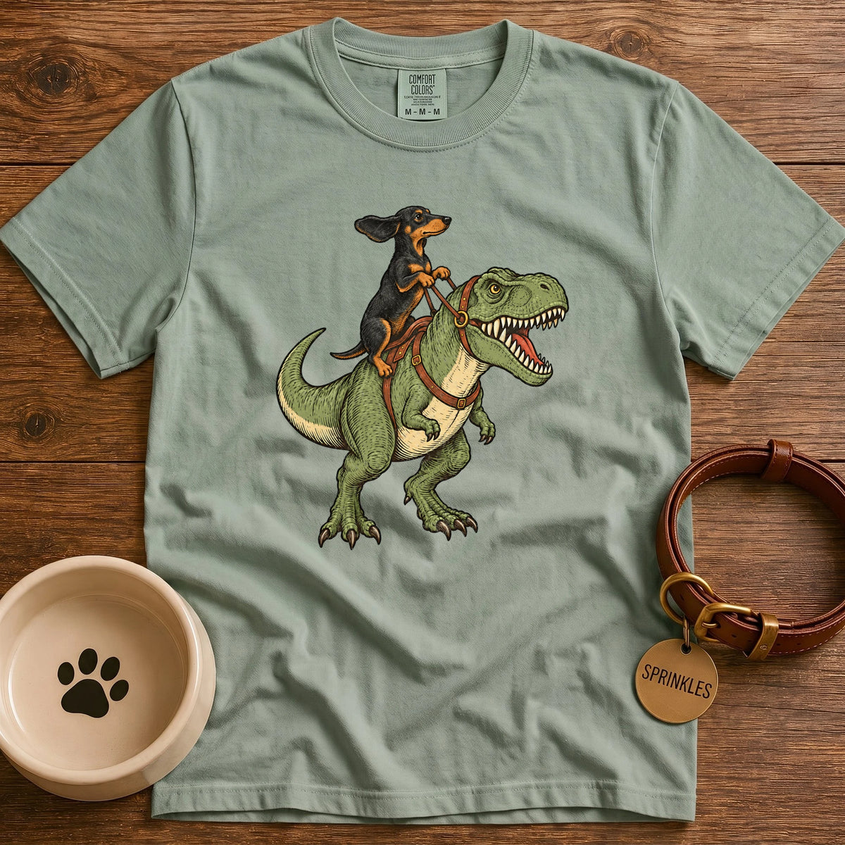 Bay Vintage-style illustration of a red dachshund riding a green T-Rex dinosaur, holding leather reins, with windblown ears and detailed hand-drawn artwork.