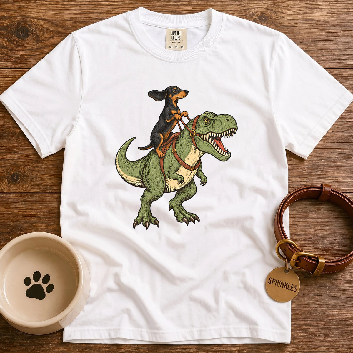 White Vintage-style illustration of a red dachshund riding a green T-Rex dinosaur, holding leather reins, with windblown ears and detailed hand-drawn artwork.